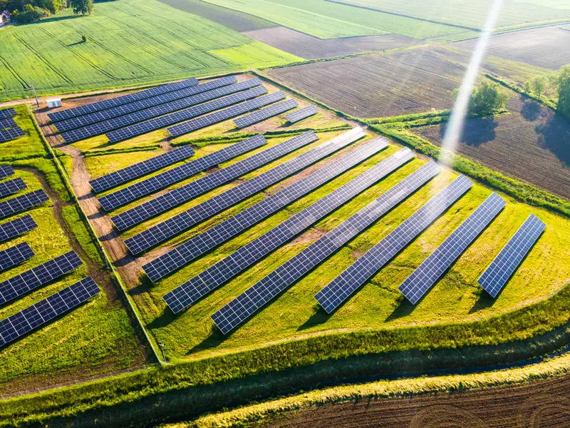 Vue aérienne d'une centrale photovoltaïque au sol bordée de parcelles cultivées